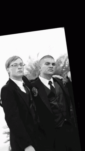 two men in suits are standing next to each other in a black and white photo