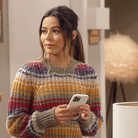 a woman wearing a striped sweater holds a cell phone