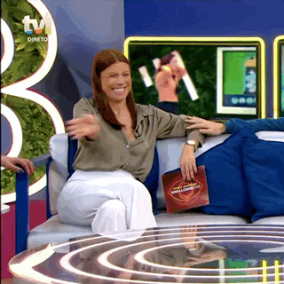 a woman is sitting on a couch in front of a tv holding a magazine that says ' direto ' on it