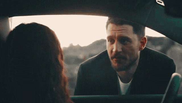 a man and woman are looking at each other in a car with the number 0 on the back window