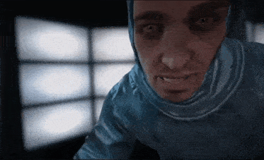 a man in a blue suit with a hood looks at the camera