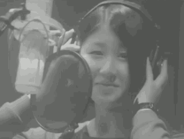 a woman singing into a microphone with headphones on