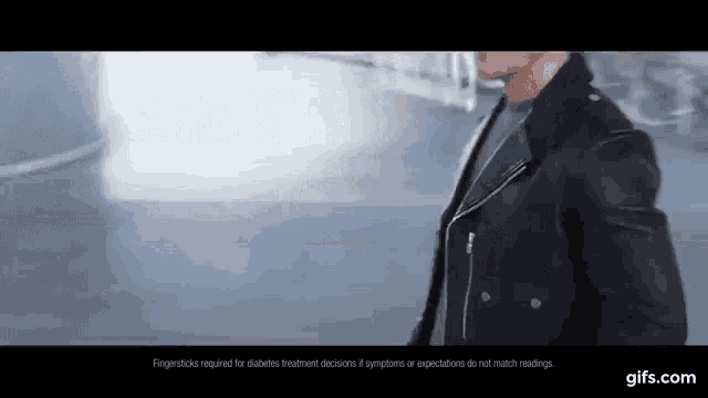 a man in a leather jacket is walking down the street .