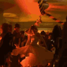 a woman in a white dress is dancing in a crowd