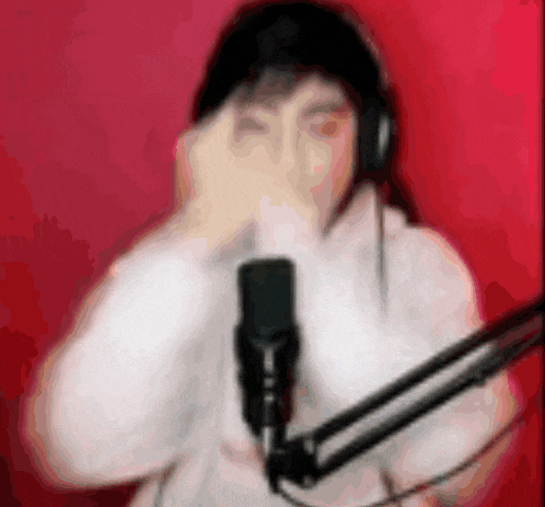 a blurry picture of a person wearing headphones and a white hoodie standing in front of a microphone