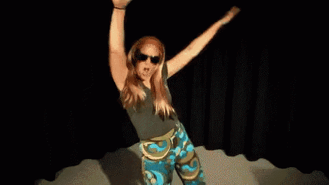 a woman wearing headphones and sunglasses is dancing with her arms in the air