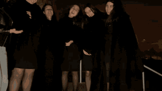 a group of women in black dresses pose for a photo