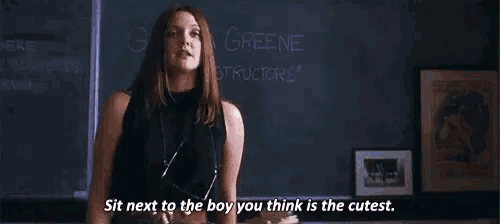 a woman is standing in front of a blackboard and talking to a boy .