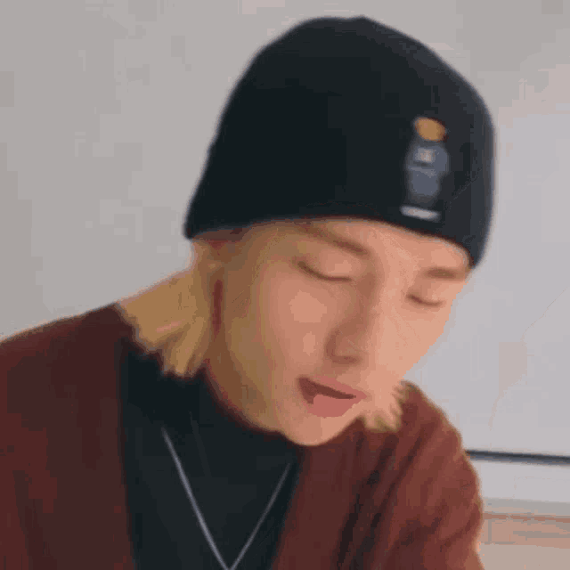 a close up of a person wearing a beanie and a cardigan .