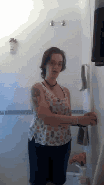 a woman with a tattoo on her arm is standing in a bathroom holding a towel