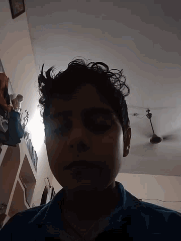 a man with curly hair looks down at something in a dark room
