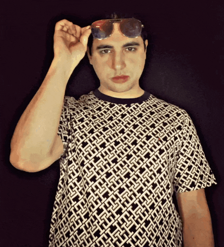 a man wearing sunglasses and a black and white shirt with a geometric pattern