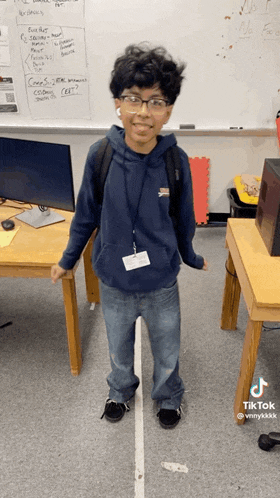 a boy wearing glasses and a name tag is standing in front of a white board that says no parking
