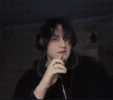 a man wearing headphones and a ring on his finger smoking a cigarette