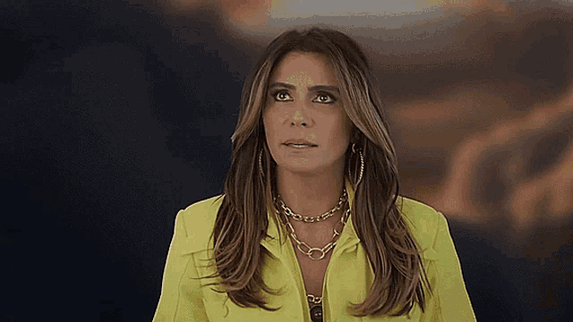 a woman wearing a yellow jacket and gold necklace