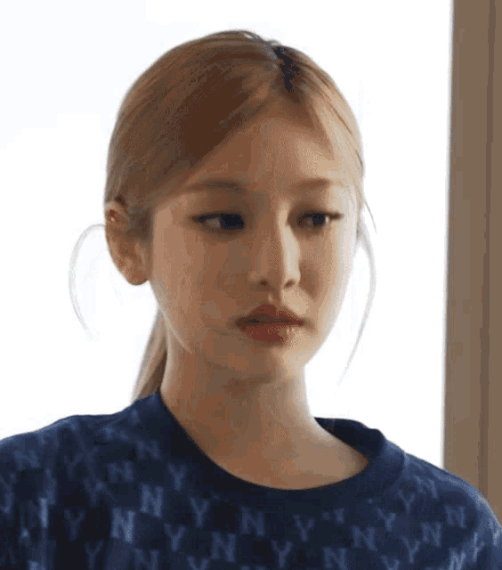 a close up of a woman 's face wearing a blue sweater with ny on it