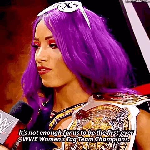 a woman with purple hair and a wwe women 's tag team championship belt