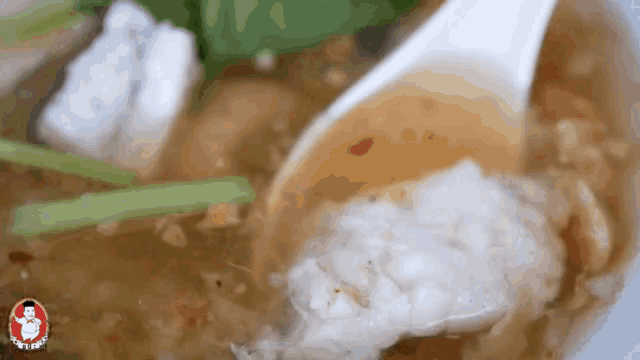 a close up of a spoon in a bowl of soup with a picture of a chef on the bottom