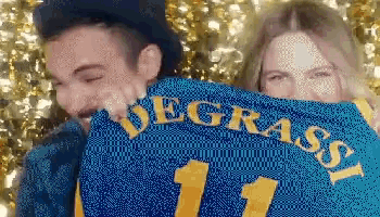 a man and a woman are hugging and the man is wearing a blue jersey with the number 11 on it