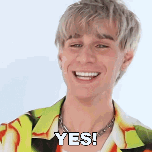 a young man in a colorful shirt is smiling and says yes