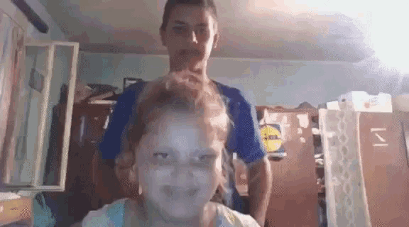 a boy is giving a girl a haircut in a room .