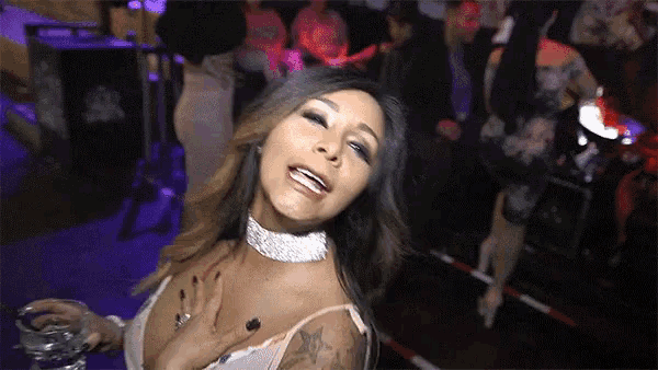 a woman in a very revealing top is holding a shot glass