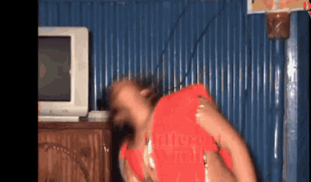 a woman in a red top is dancing in front of a tv screen that says different world on it