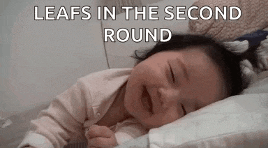 a baby is crying while laying on a pillow in bed .