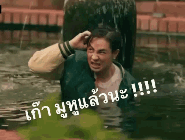a man is standing in the water with his hand on his head and making a face .