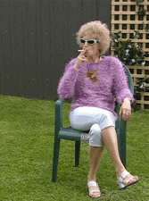 a woman in a purple sweater is smoking a cigarette while sitting in a chair