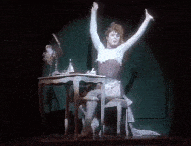 a woman is sitting at a table with her arms outstretched .