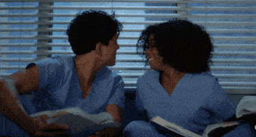 a man and a woman in scrubs look at each other in front of a window