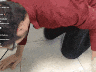 a man in a red shirt is kneeling down on a tiled floor