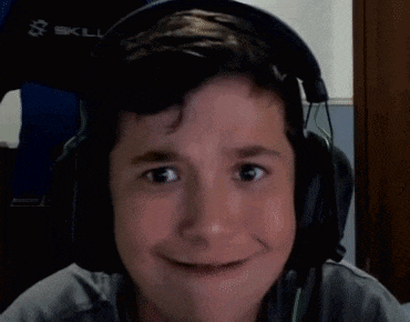 a young boy wearing headphones is making a funny face while looking at the camera .
