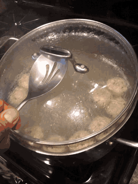 a person is holding a spoon over a pot of food