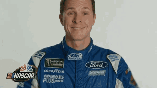 a man wearing a ford racing suit is smiling for the camera