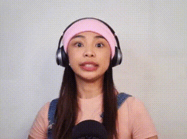 a woman wearing headphones and a pink hat is making a face .