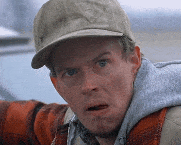 a man wearing a hat and a plaid shirt is making a funny face
