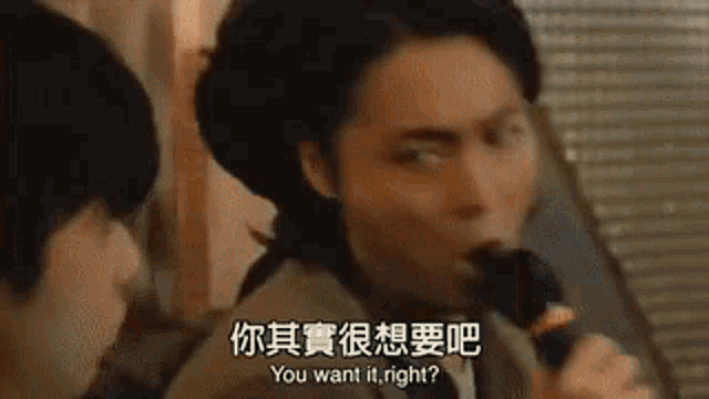 a man is singing into a microphone in a foreign language while another man looks on .
