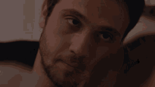 a close up of a man 's face with a beard looking at something