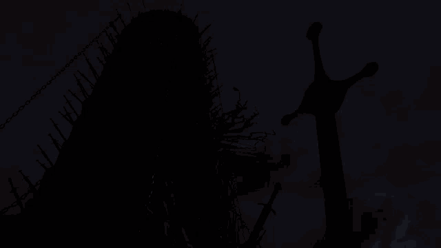 a sword is silhouetted against a sunset sky