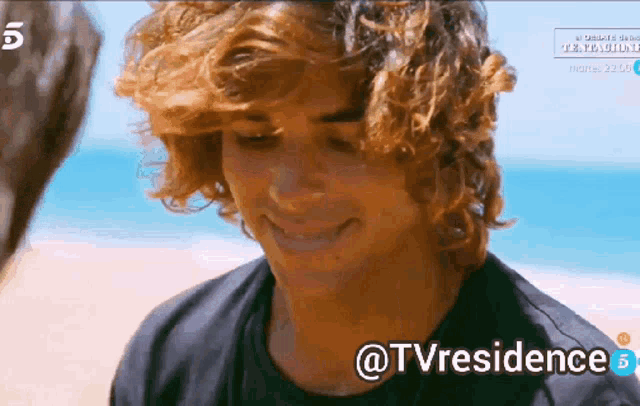 a man with curly hair is smiling in front of the ocean with the hashtag @tvresidence