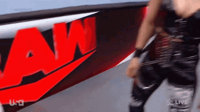 a man playing a guitar in front of a raw sign