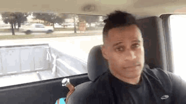 a man in a black shirt is sitting in the back seat of a truck .