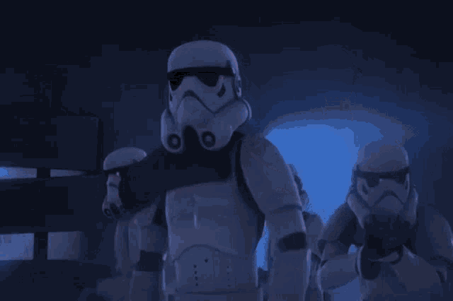 a group of stormtroopers are standing next to each other in a dark room holding lightsabers .