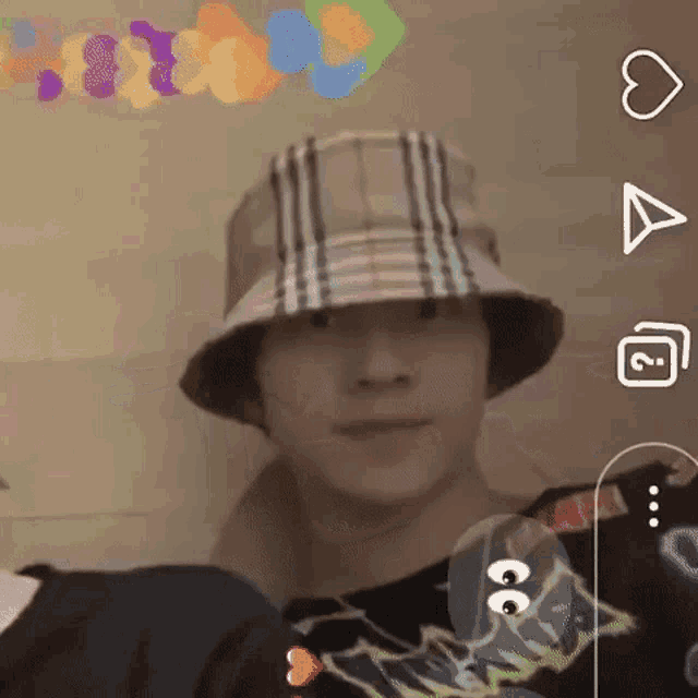 a man wearing a plaid bucket hat and a black shirt