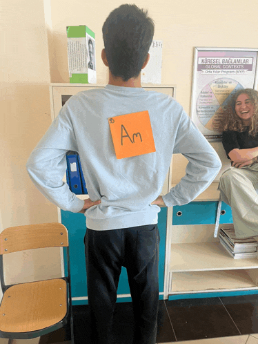 a man with a sticky note on his back that says am