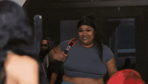 two women are standing next to each other in a living room . one of the women is wearing a black nike shirt .