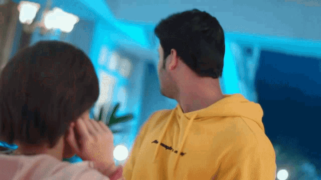 a man in a yellow hoodie is talking to a girl