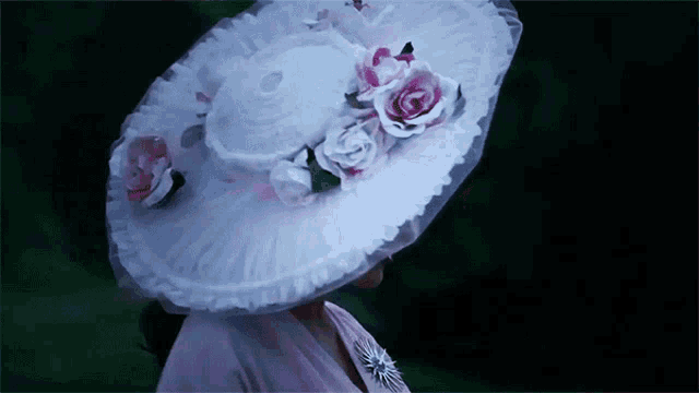 a woman wearing a large white hat with pink flowers